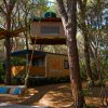 Bungalow in legno tra gli alberi con un’altalena e una tenda sospesa.