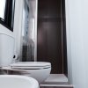Bagno moderno con doccia, WC e lavabo di colore bianco.
