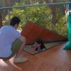 Persona su un terrazzo in legno con pouf verdi e botola aperta.