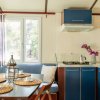Cucina e sala da pranzo di una casa mobile, con mobili blu e tavolo apparecchiato.