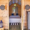 Interno di cabina di legno con letto, lampada blu e sedia pieghevole.