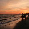 Due persone camminano su una spiaggia al tramonto.