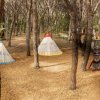 Due tende a forma di tipì colorati tra gli alberi, con totem decorativi su un lato.