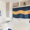 Una camera da letto con letto matrimoniale, cuscini bianchi e decorazione murale blu e arancione.