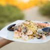 Un piatto di spaghetti ai frutti di mare con gamberi, cozze e calamari su un piatto quadrato.