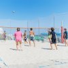 Gruppo di persone gioca a pallavolo sulla sabbia.