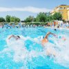 Due persone nuotano in una piscina affollata.