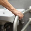 Mano che afferra una barra di supporto in un bagno.