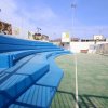 Gradinate blu affiancano un campo sportivo all'aperto.