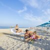 Famiglia gioca sulla spiaggia, sotto ombrelloni blu.