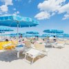 Lettini e ombrelloni blu sulla spiaggia soleggiata.