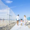 Famiglia passeggia sulla spiaggia sotto cieli blu.