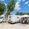 Caravan e tenda sotto gli alberi in un campeggio.