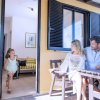Bambina che corre verso due adulti seduti su una patio.