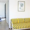 Soggiorno con cucina, divano a righe e TV a muro.