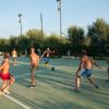 Giocatori impegnati in una partita di calcetto all'aperto su campo in cemento.