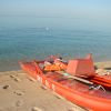 Una barca rossa su una spiaggia di sabbia, con il mare calmo sullo sfondo.