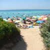 Spiaggia affollata con ombrelloni colorati e tante persone che si godono il mare.