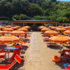 Spiaggia con ombrelloni arancioni e lettini sulla sabbia.