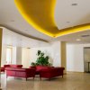 Interno spazioso con soffitto illuminato, divani rossi, piante e decorazioni eleganti.
