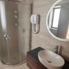Bagno moderno con doccia angolare, grande specchio rotondo e lavabo bianco.