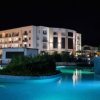 Hotel moderno illuminato di notte, con piscina e area relax.