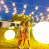 Due bambini in un giardino di sera, circondati da luci decorative.