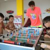 Bambini giocano a biliardino con un adulto in una stanza decorata con scritte colorate.