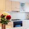 Cucina luminosa con fiori colorati in primo piano, mobili in legno e lavello.
