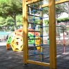 Struttura da arrampicata in legno e corda, con giochi colorati sullo sfondo.