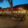 Ristorante all'aperto con tetto rosso, luci soffuse e persone sedute.