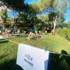 Gruppo di persone fa yoga su un prato verde in una zona fitness all'aperto, circondata da alberi.