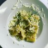 Un piatto di pasta con zucchine e formaggio grattugiato.