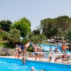 Persona fa un tuffo in piscina. Persone attorno guardano.