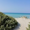 Spiaggia con mare turchese e dune di sabbia.