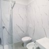 Bagno con doccia e pareti effetto marmo.