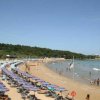 Spiaggia con file di ombrelloni e bagnanti in mare.
