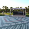 Una piazza con piastrelle a motivi geometrici e un palco tra palme.