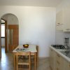 Una cucina semplice con tavolo di legno, sedie, lavandino e fornelli.