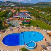 Una piscina con lettini e ombrelloni, circondata da palme e vegetazione.