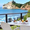 Tavolo bianco con colazione, vista mare e ombrelloni blu su spiaggia.