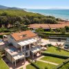 Una villa moderna con giardino vicino a una spiaggia e mare blu, vista dall'alto.