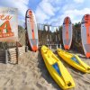 Tavole da surf e kayak sulla sabbia con insegna 