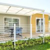 Una casetta con veranda coperta, mobili da esterno e giardino curato.