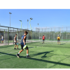 Persone giocano a padel in un campo recintato, cielo terso.