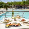 Tavolo con piatti gourmet e vino bianco accanto a una piscina.