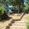 Scalini in pietra con auto e vegetazione al di sopra.