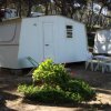 Casetta bianca con sedie vicino a un tavolo in un ambiente boschivo.