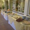Buffet con vari piatti su tavoli, piatti impilati ai lati.