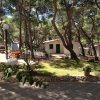 Casetta bianca in un bosco con sedie all'aperto e prato curato.